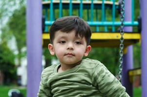 mignonne asiatique pakistanais bébé est profiter le magnifique ensoleillé journée à mise en garde les enfants et Publique parc de luton ville de Angleterre Royaume-Uni. faible angle image a été capturé sur avril 03ème, 2023 photo