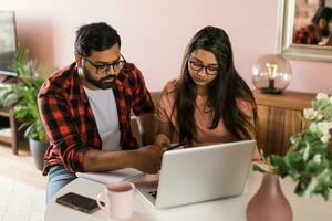 millénaire Indien mari et épouse Faire national formalités administratives, comptabilité emploi et révision papier factures, Reçus à portable ordinateur, en utilisant en ligne calculatrice - économique crise concept photo