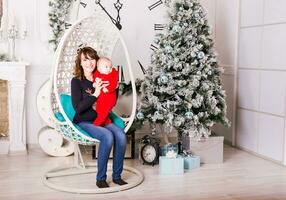 portrait de souriant Jeune mère avec bébé près Noël arbre photo