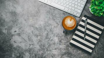 Haut voir, foncé Bureau bureau avec clavier ordinateur, tasse de café, stylo et carnet de notes, copie espace, moquer en haut.. photo