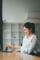 Jeune femme en portant crédit carte et en utilisant portable ordinateur. femme d'affaires travail à maison. en ligne achats, commerce électronique, l'Internet bancaire, dépenses argent. photo