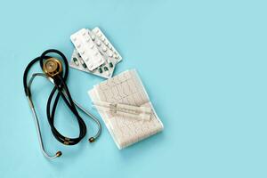 phonendoscope, cardiogramme , seringues et pilules sur une bleu Contexte moderne médicament photo
