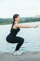 Jeune femme dans noir tenue de sport exercice en plein air. aptitude et en bonne santé mode de vie concept. le blanc fille Est-ce que des sports dans le parc. photo