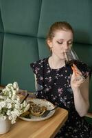 magnifique Jeune femme en buvant rouge du vin dans restaurant photo
