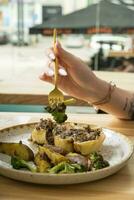 proche en haut de une fourchette dans une femme main plus de une assiette avec délicieux nourriture dans une restaurant photo