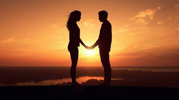 couple en portant mains orienté vers chaque autre à le coucher du soleil. silhouette concept photo