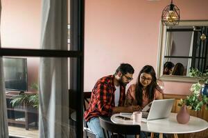 millénaire Indien mari et épouse Faire national formalités administratives, comptabilité emploi et révision papier factures, Reçus à portable ordinateur, en utilisant en ligne calculatrice - économique crise concept photo