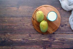 mangue mûre fraîche et verre de lait sur table photo