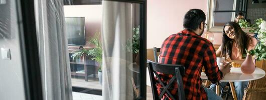 bannière Jeune diverse aimant couple en mangeant croissant et pourparlers ensemble à Accueil dans petit déjeuner temps copie espace. la communication et relation concept photo