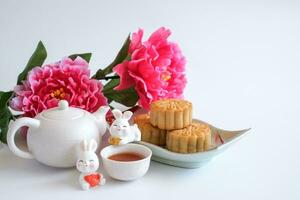 chinois milieu de l'automne Festival concept fabriqué de gâteaux de lune, thé décoré avec prune fleur et lapins isolé sur blanc Contexte. photo