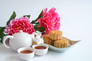 chinois milieu de l'automne Festival concept fabriqué de gâteaux de lune, thé décoré avec prune fleur et lapins isolé sur blanc Contexte. photo