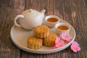 chinois milieu de l'automne Festival concept fabriqué de gâteaux de lune, thé décoré avec prune fleur et lapins sur en bois Contexte. photo