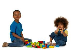 deux peu mignonne africain américain les enfants en jouant sur le sol avec beaucoup de coloré Plastique blocs dans studio, isolé sur blanc Contexte photo