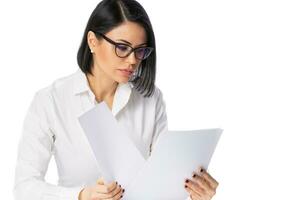 pensif Jeune affaires femme dans des lunettes et blanc chemise sur sa bureau avec papier documents. réussite affaires carrière concept. photo