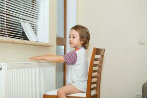 une enfant séance sur une chaise près une radiateur photo