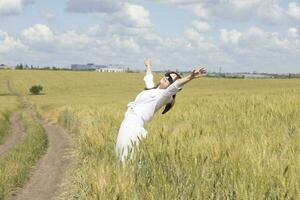 une femme dans une blanc robe permanent dans une champ photo