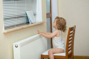 une enfant séance sur une chaise près une radiateur photo