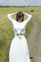 une femme dans une blanc robe permanent dans une champ photo