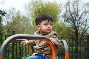 mignonne asiatique pakistanais bébé est profiter le magnifique ensoleillé journée à mise en garde les enfants et Publique parc de luton ville de Angleterre Royaume-Uni. faible angle image a été capturé sur avril 03ème, 2023 photo