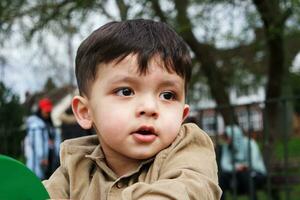 mignonne asiatique pakistanais bébé est profiter le magnifique ensoleillé journée à mise en garde les enfants et Publique parc de luton ville de Angleterre Royaume-Uni. faible angle image a été capturé sur avril 03ème, 2023 photo