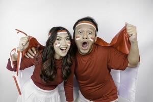 une Jeune asiatique couple avec une content réussi expression portant rouge Haut et Bandeau tandis que en portant l'indonésie drapeau, isolé par blanc Contexte. l'indonésie indépendance journée concept. photo