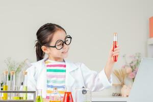 asiatique peu fille travail avec tester tube science expérience dans blanc salle de cours photo