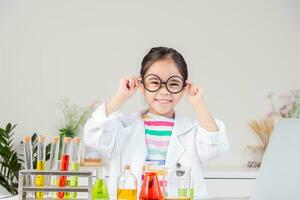 asiatique peu fille travail avec tester tube science expérience dans blanc salle de cours photo