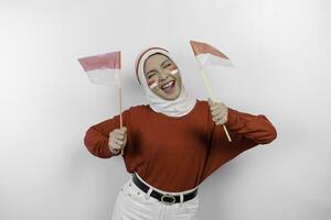 une Jeune asiatique musulman femme avec une content réussi expression portant rouge Haut et blanc hijab tandis que en portant l'indonésie drapeau, isolé par blanc Contexte. l'indonésie indépendance journée concept. photo