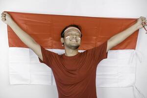 content souriant indonésien homme en portant l'indonésie drapeau à célébrer Indonésie indépendance journée isolé plus de blanc Contexte. photo