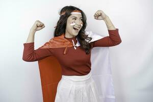 excité asiatique femme portant une rouge haut, drapeau cap et Bandeau, montrant fort geste par levage sa bras et muscles souriant fièrement. l'indonésie indépendance journée concept. photo