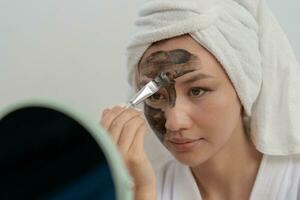 femme asseoir dans de face de une miroir. visage de une en bonne santé femme appliquant crème et se maquiller. publicité pour peau crème, anti-rides, bébé affronter, blanchiment, Crème hydratante, serrer les pores sérum photo