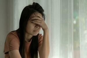 malheureuse femme asiatique fille déçue, triste à cause d'un problème à la maison seule, se sentir seule, stressée, souffrant d'une mauvaise relation, rompre, divorcer, femme confuse, dépression santé mentale, solitude photo