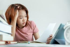 une étudiante asiatique a de l'anxiété à cause des examens, les femmes se préparent aux tests et apprennent les leçons à la bibliothèque. stress, désespoir, hâte, incompréhension lecture, découragement, attente, connaissance photo