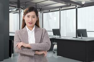 portrait professionnel Jeune asiatique affaires femme qui porte formel costume Bureau ouvrier est souriant et bras traversée travail réussi en toute confiance avec des stands seul dans le Bureau chambre. photo