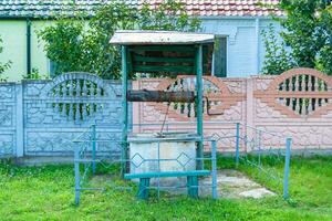 Vieux puits avec seau en fer sur longue chaîne forgée pour l'eau potable photo