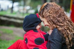 magnifique Jeune mère en jouant en plein air avec sa peu bébé fille portant une coccinelle costume. Halloween concept. maternité concept. photo