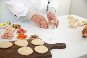 Sénior femme élongation mini Pizza pâte. délicieux Accueil fabriqué mini pizzas préparation. photo