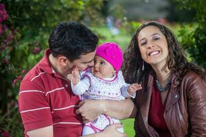 Jeune Parents ayant amusement en plein air avec leur six mois vieux bébé fille. bonheur concept. famille concept photo