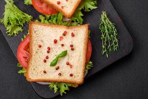délicieux sandwich avec griller, jambon, tomates, fromage et salade photo