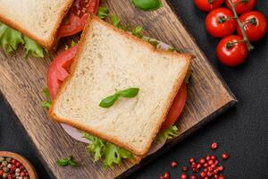 délicieux sandwich avec griller, jambon, tomates, fromage et salade photo