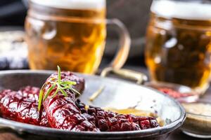 grillé chaud saucisses servi dans une chaud la poêle avec Frais Romarin suivant à deux Brouillon bières photo