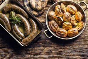 rôti saucisses dans la poêle avec Romarin et patates.. traditionnel européen nourriture bratwurst jaternice ou jirnice photo