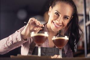 Jeune barmaid sourit après fabrication deux Expresso martini court les boissons avec une café photo