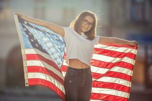 content Jeune américain école fille en portant et agitant dans le ville avec Etats-Unis drapeau photo