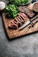 tranches de juteux grillé du boeuf steak avec fourchette et couteau sur une Boucher assiette photo