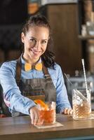 souriant barmaid sert Frais vieux façonné cocktail sur une bar dans un ornemental verre photo