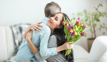 Jeune mère recevoir une bouquet plein de tulipes de le sien fils pendant nationale aux femmes journée photo