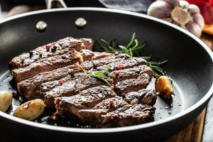 juteux et grillé du boeuf nervure œil steak dans téflon la poêle avec sel, poivre et Romarin herbes photo