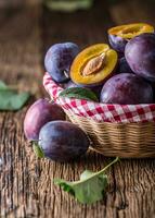 prunes. Frais juteux prunes dans une bol sur une en bois ou béton planche photo