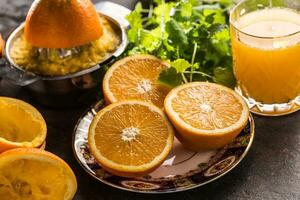 Frais des oranges presse-agrumes jus tropical des fruits et herbes sur béton planche photo